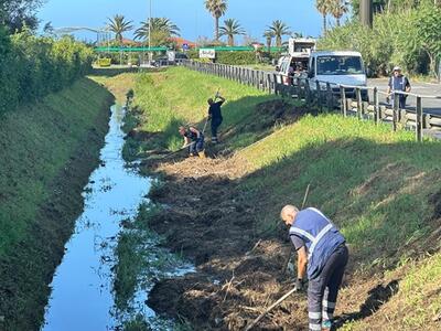 Due  operai mandati dal Consorzio per pulire l'enormità di sfalci lasciati sugli argini dei fiumi versiliesi: lo sconcerto di Emanuele Ricciardi, costretto da anni a pulire le montagne di sfalci che ostruiscono la sua darsena